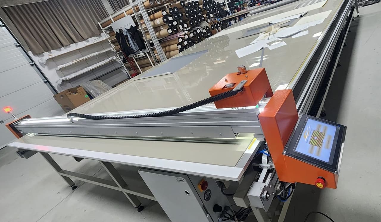 نمای نزدیک سر برش و ریل حرکتی دستگاه برش پارچه CNC روی میز کار